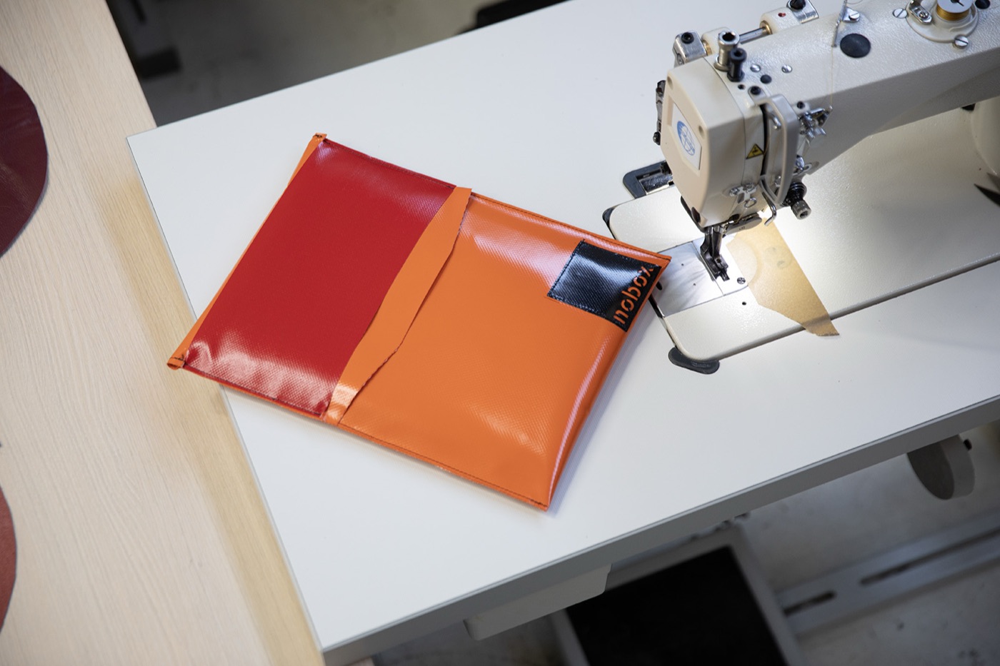 Een net genaaide, kleurrijke Nobox-verzendhoes op de naaimachine bij Atelier Revive